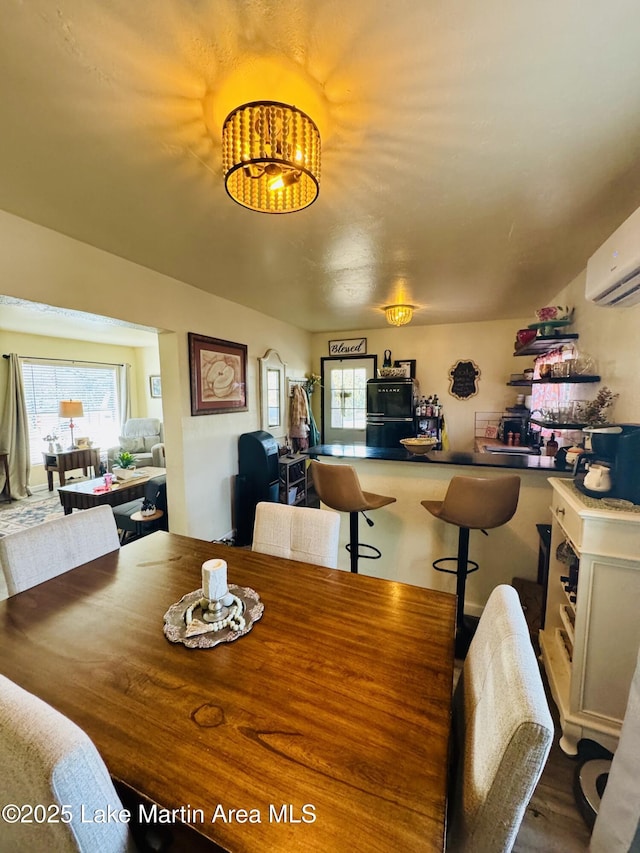 dining space with hardwood / wood-style flooring and a wall mounted air conditioner