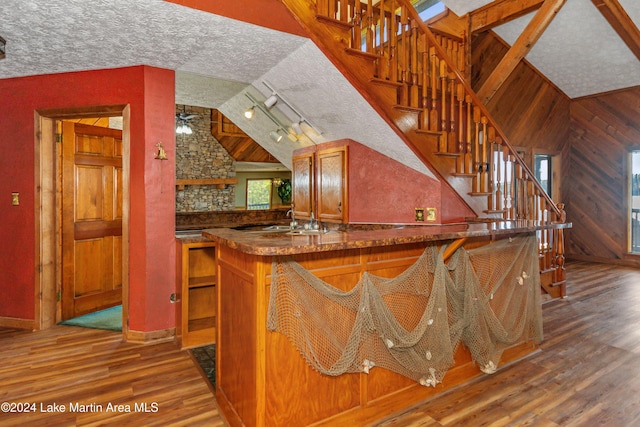 kitchen with kitchen peninsula, a textured ceiling, ceiling fan, wooden walls, and hardwood / wood-style flooring