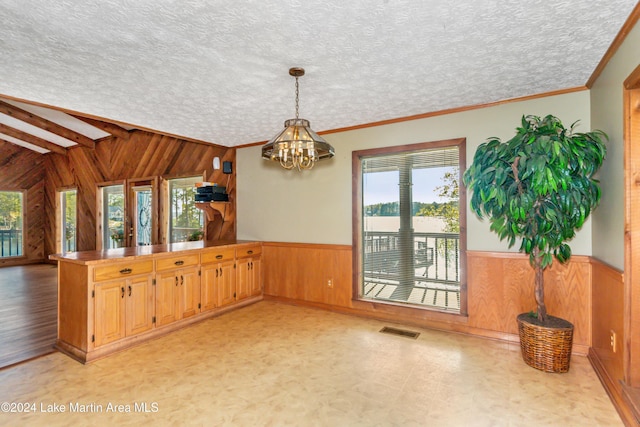 kitchen featuring a textured ceiling, an inviting chandelier, and wood walls