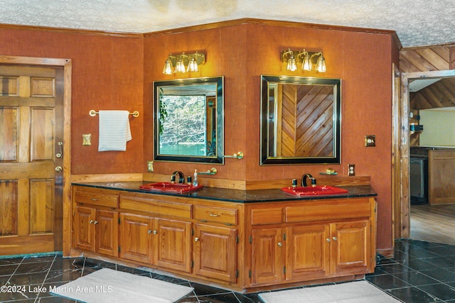 bathroom with tile patterned floors, crown molding, vanity, and a textured ceiling