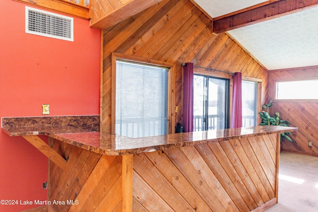 kitchen featuring vaulted ceiling with beams, wooden walls, and carpet floors