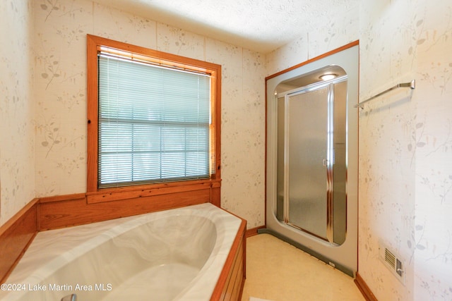 bathroom with a textured ceiling and shower with separate bathtub