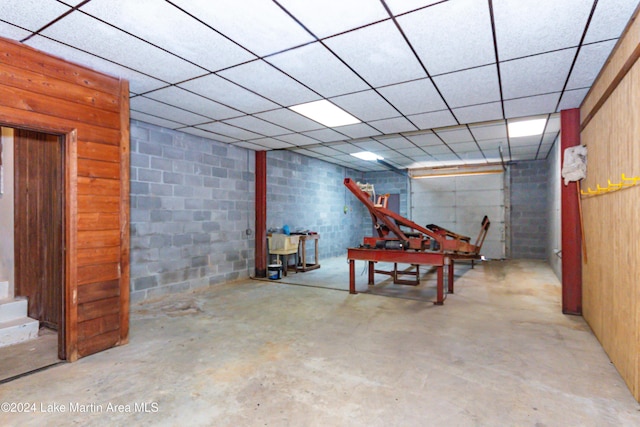 basement with a paneled ceiling and wood walls