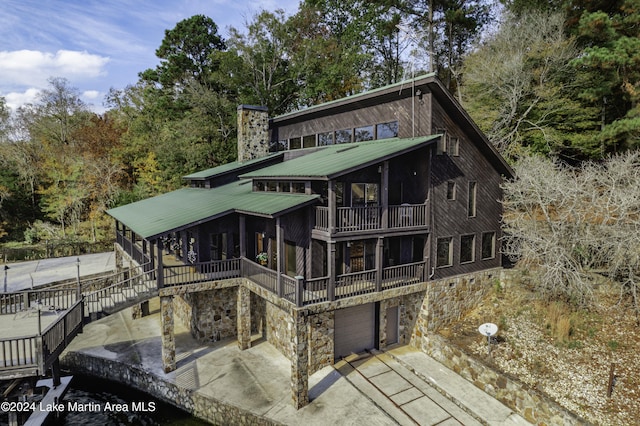 rear view of house with a balcony, a garage, and a sunroom