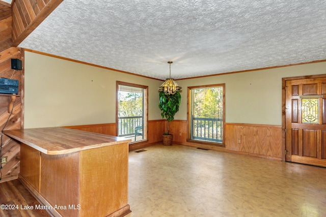 kitchen with pendant lighting, crown molding, a textured ceiling, and an inviting chandelier