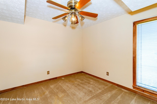 unfurnished room featuring plenty of natural light, ceiling fan, a textured ceiling, and light carpet