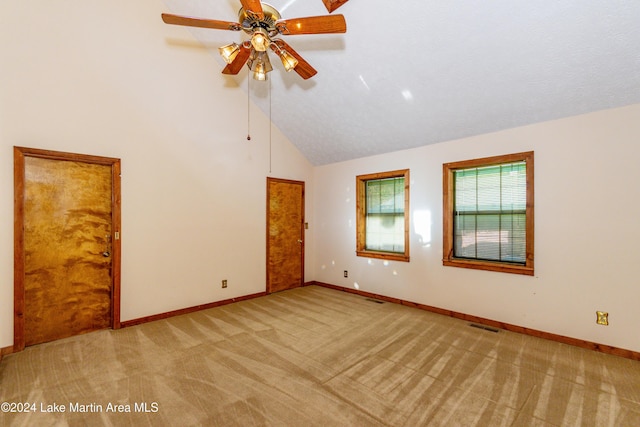 empty room with ceiling fan, high vaulted ceiling, light carpet, and a textured ceiling