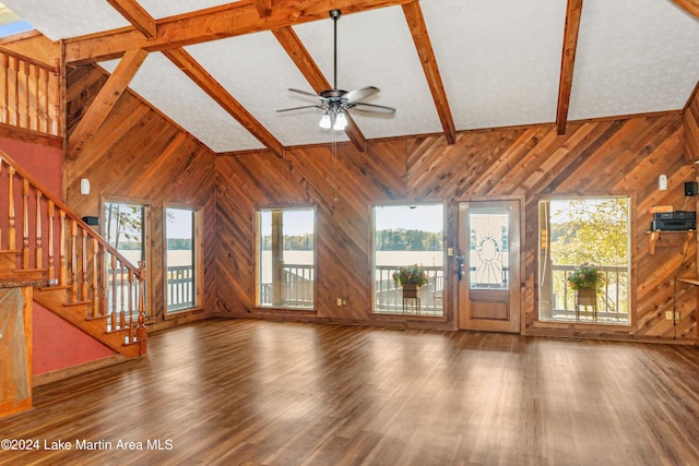 unfurnished living room featuring beamed ceiling, ceiling fan, dark wood-type flooring, and wood walls