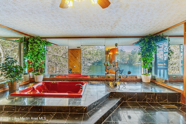 bathroom with tiled tub, ceiling fan, crown molding, and a textured ceiling