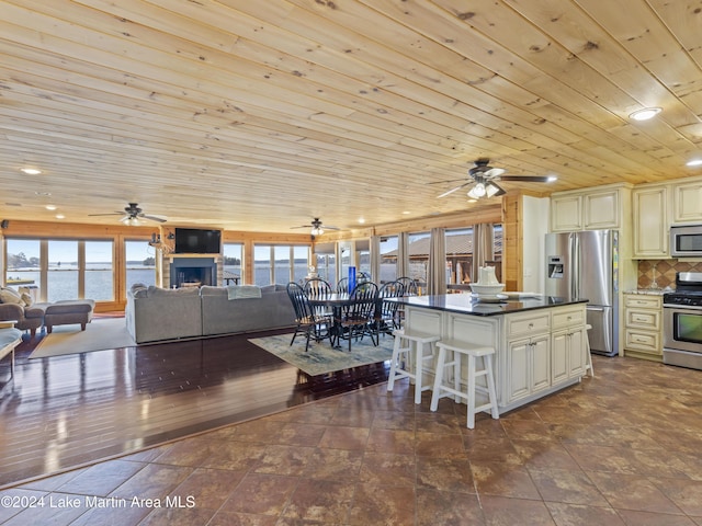 kitchen with a kitchen island, appliances with stainless steel finishes, tasteful backsplash, wood ceiling, and cream cabinetry