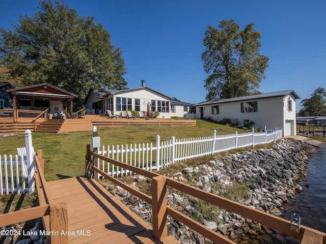 rear view of property featuring a wooden deck and a lawn