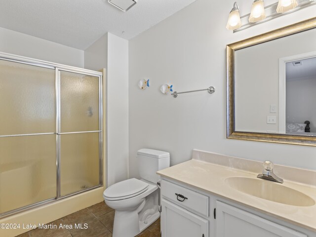 bathroom with a shower with shower door, vanity, toilet, tile patterned floors, and a textured ceiling