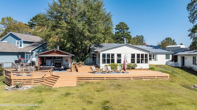 rear view of house featuring a wooden deck, a yard, and a sunroom