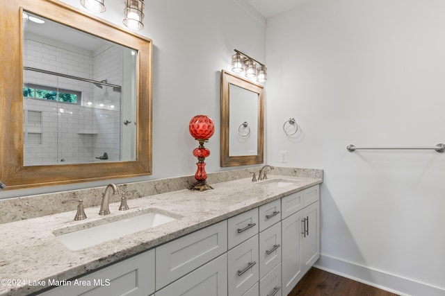 bathroom with hardwood / wood-style flooring, vanity, and tiled shower