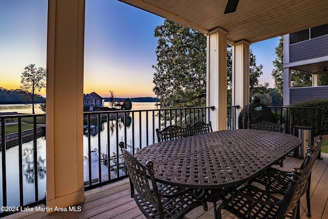 deck at dusk featuring a water view and ceiling fan