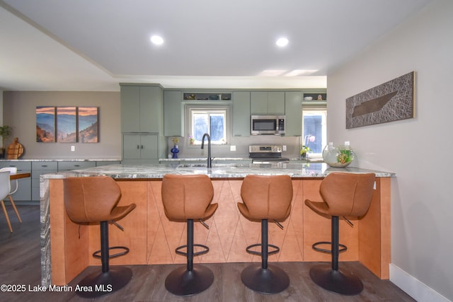 kitchen featuring a sink, dark wood-type flooring, appliances with stainless steel finishes, and green cabinetry
