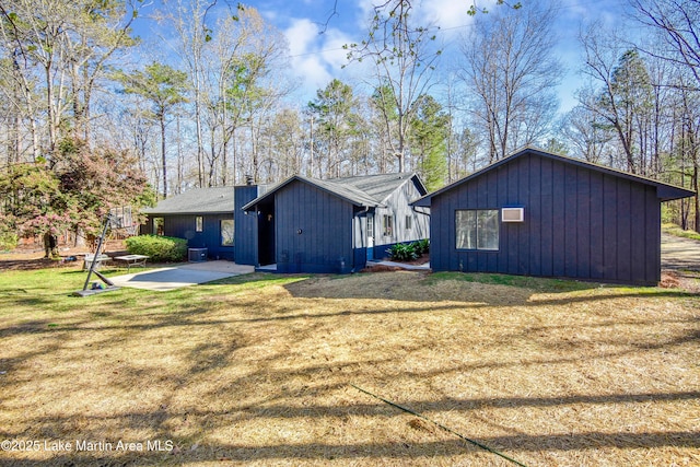 view of side of property featuring a yard, a patio, and board and batten siding