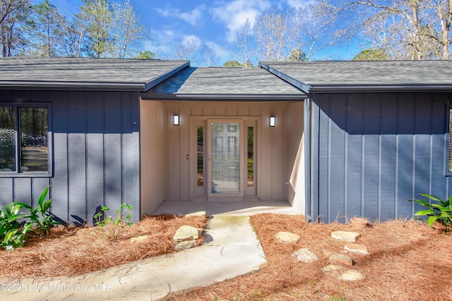 doorway to property featuring board and batten siding and a shingled roof