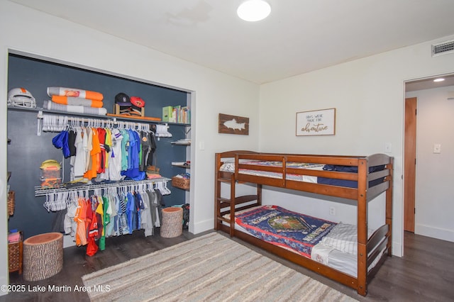 bedroom featuring a closet, visible vents, baseboards, and wood finished floors