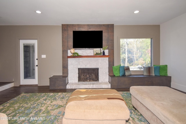 living area featuring recessed lighting, baseboards, a stone fireplace, and wood finished floors