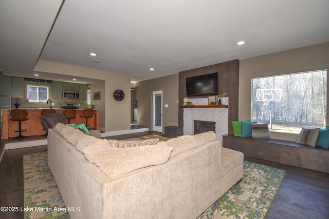 living room featuring dark wood-style floors, recessed lighting, and a fireplace