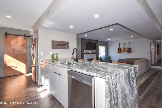 kitchen featuring a sink, wood finished floors, white cabinetry, stainless steel appliances, and a barn door