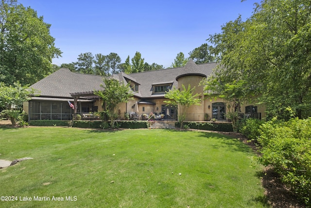 view of front of house featuring a sunroom and a front yard