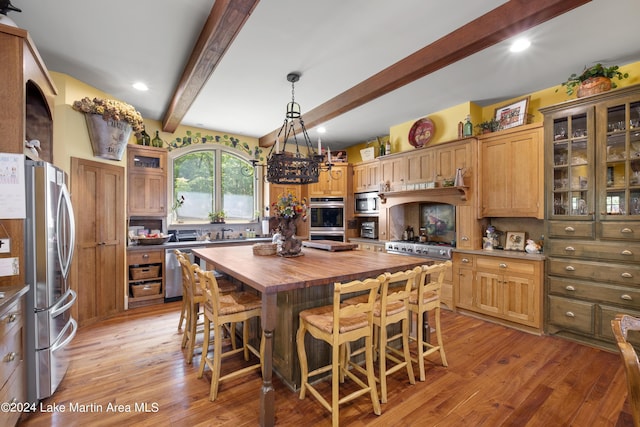 kitchen featuring beam ceiling, stainless steel appliances, wood counters, light hardwood / wood-style floors, and a kitchen island