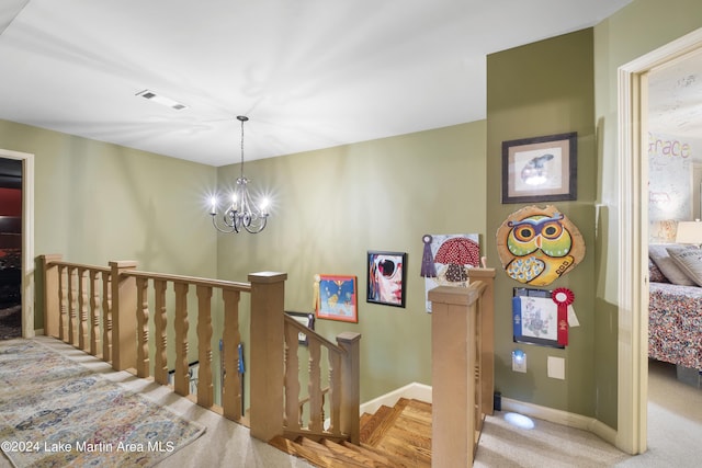 stairway with carpet flooring and an inviting chandelier