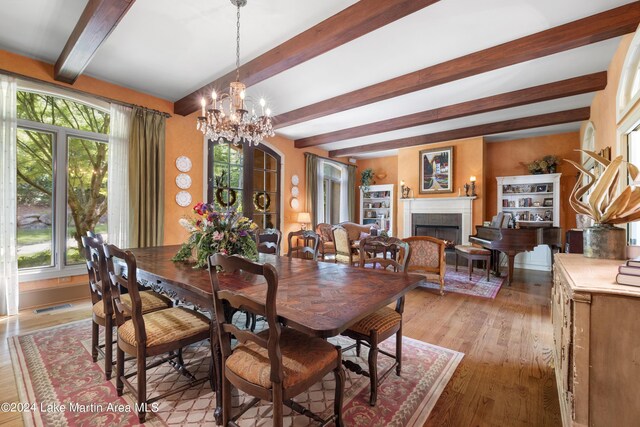 dining space featuring beamed ceiling, plenty of natural light, light wood-type flooring, and a chandelier