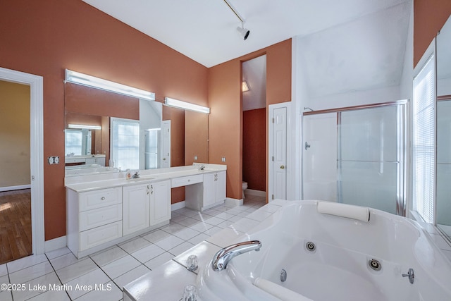 bathroom featuring baseboards, toilet, a jetted tub, tile patterned flooring, and vanity