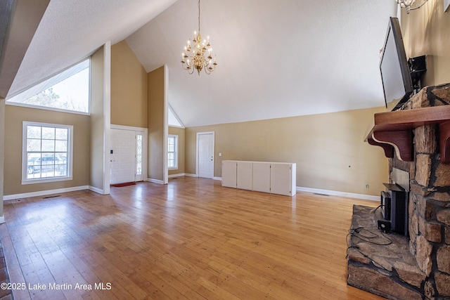 living area with a chandelier, a wealth of natural light, a fireplace, and light wood-style flooring