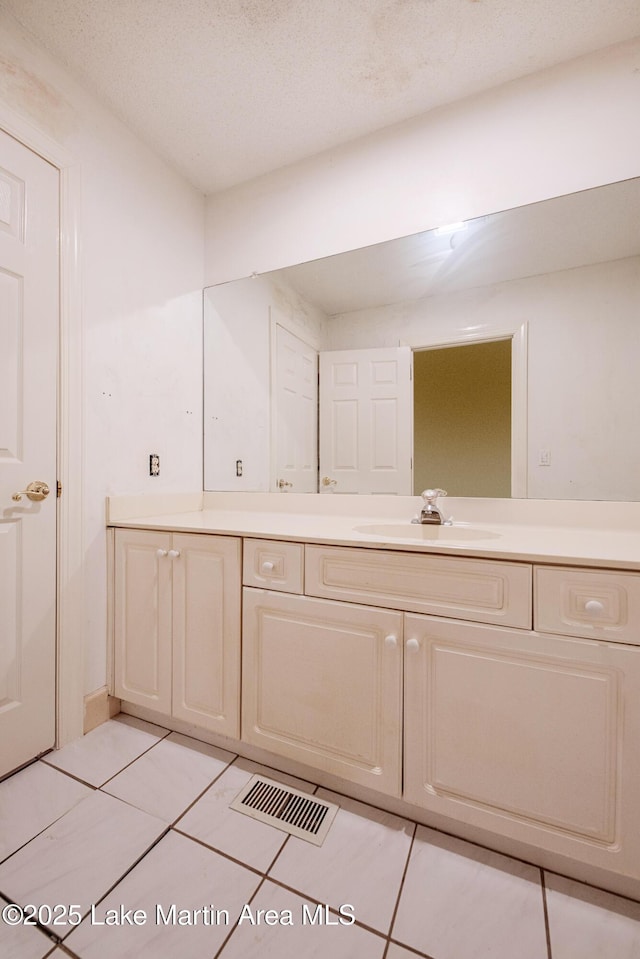 bathroom with a textured ceiling, visible vents, vanity, and tile patterned floors