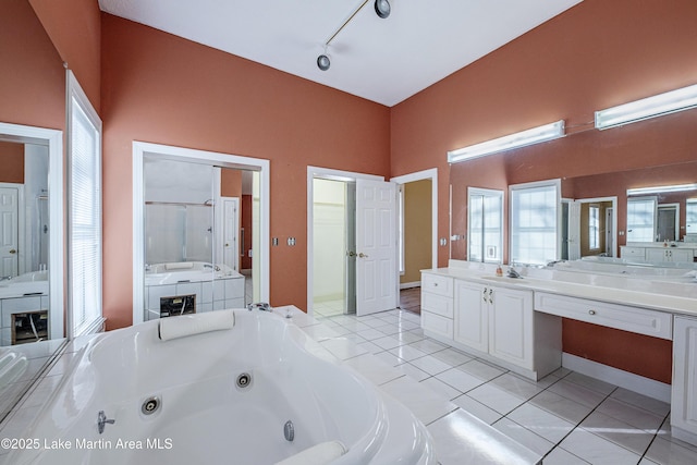 full bath featuring track lighting, a jetted tub, vanity, and tile patterned floors