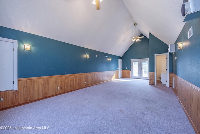 unfurnished room featuring french doors, wainscoting, and wood walls