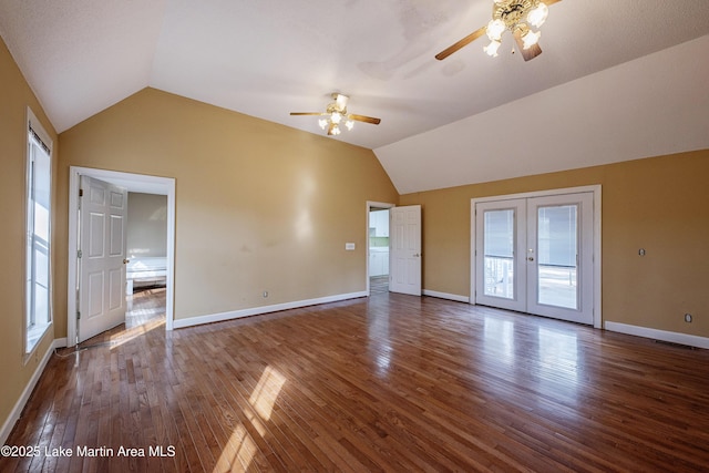 interior space with a ceiling fan, dark wood-style flooring, vaulted ceiling, and baseboards