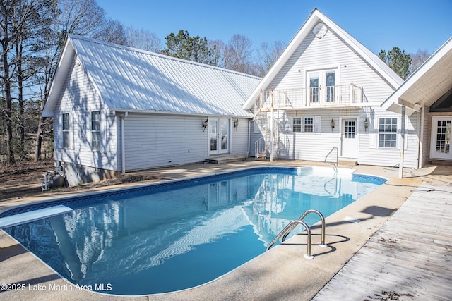 outdoor pool with a diving board and french doors