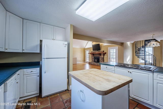 kitchen with white appliances, a fireplace, white cabinets, and open floor plan