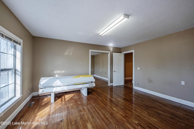 interior space featuring visible vents, a textured ceiling, baseboards, and dark wood-type flooring