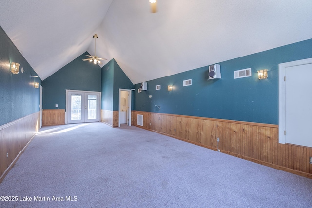 interior space with visible vents, wainscoting, vaulted ceiling, french doors, and wood walls