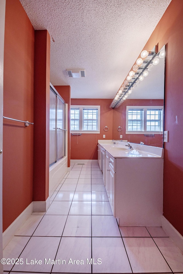 full bath with tile patterned flooring, visible vents, a textured ceiling, and double vanity