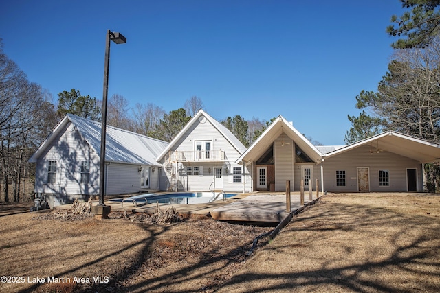 rear view of property with metal roof and an outdoor pool