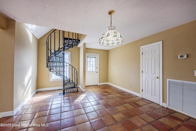 entrance foyer with baseboards, visible vents, stairs, a textured ceiling, and dark tile patterned floors