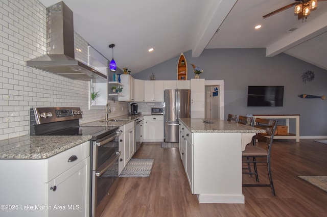 kitchen featuring appliances with stainless steel finishes, a kitchen island, ventilation hood, white cabinetry, and a breakfast bar area
