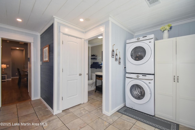 laundry area featuring light tile patterned flooring, ornamental molding, and stacked washer / dryer