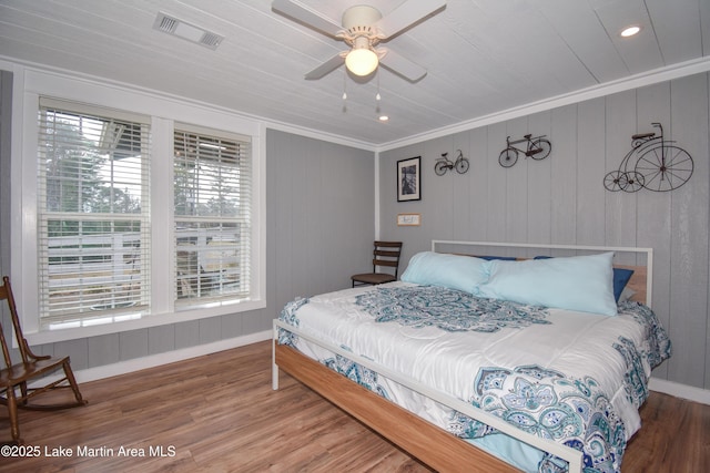 bedroom featuring hardwood / wood-style flooring, ornamental molding, and ceiling fan