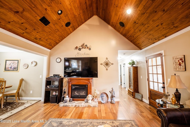 living room with wooden ceiling, a glass covered fireplace, crown molding, baseboards, and wood finished floors