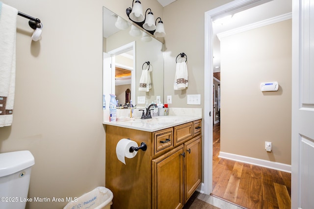 half bath featuring toilet, wood finished floors, vanity, and baseboards