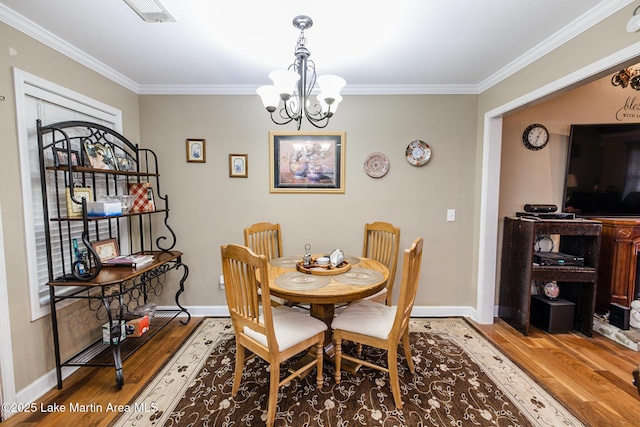 dining room featuring ornamental molding, an inviting chandelier, wood finished floors, and baseboards