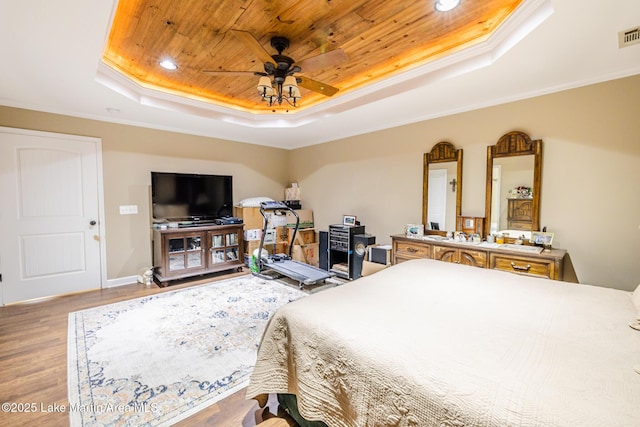 bedroom with ornamental molding, wooden ceiling, wood finished floors, and a raised ceiling